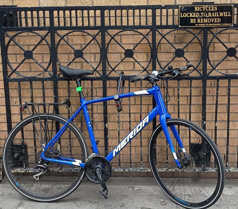 A locked bicycle with a sign for no locked bicycles. An example of precarious entitlement
